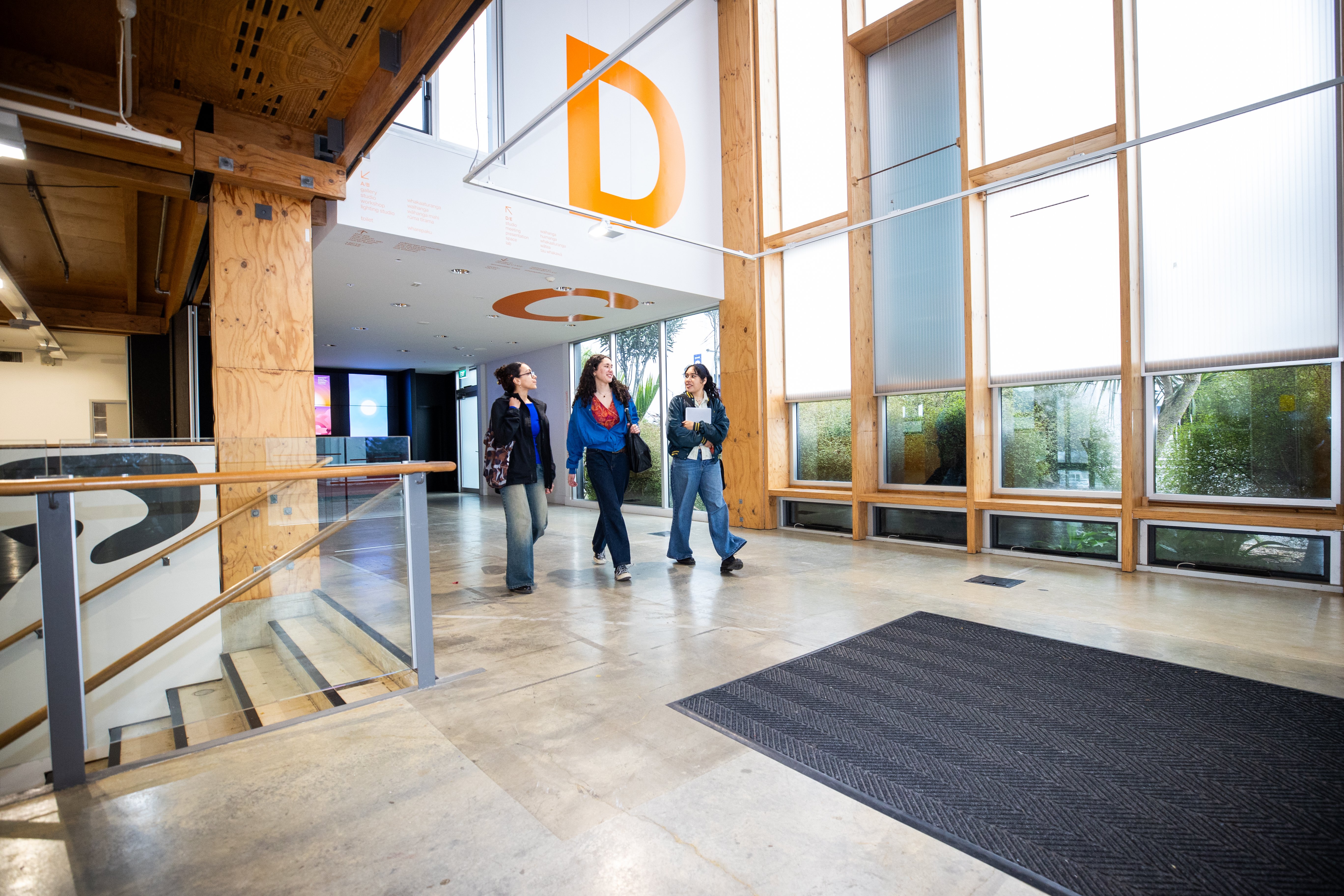 Wide shot of three students walking up the steps inside a University building