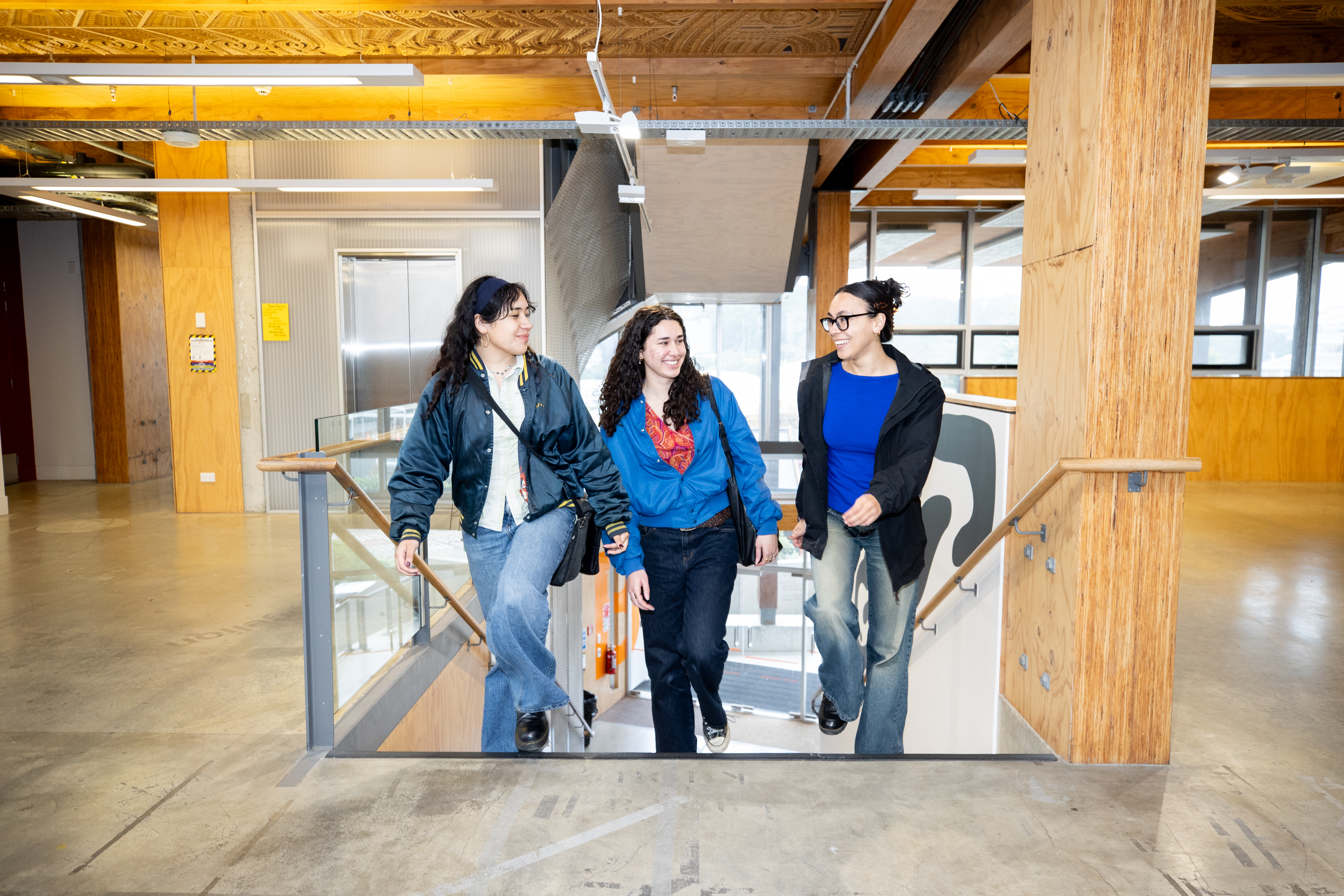 Three students walking up the steps inside a University building