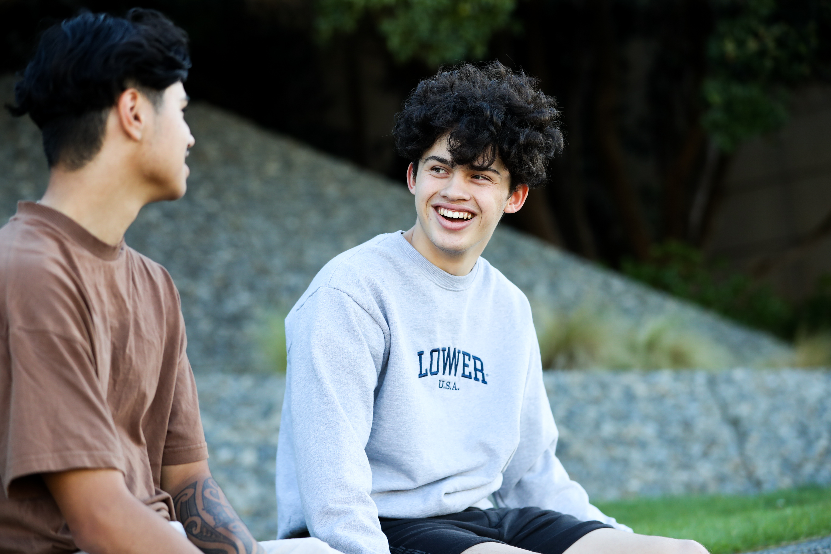 two young tāne sitting and talking outside