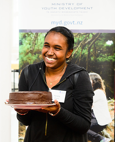 Ranisha holds out a chocolate cake in celebration of her 17th birthday at the New Zealand Youth Awards 2018
