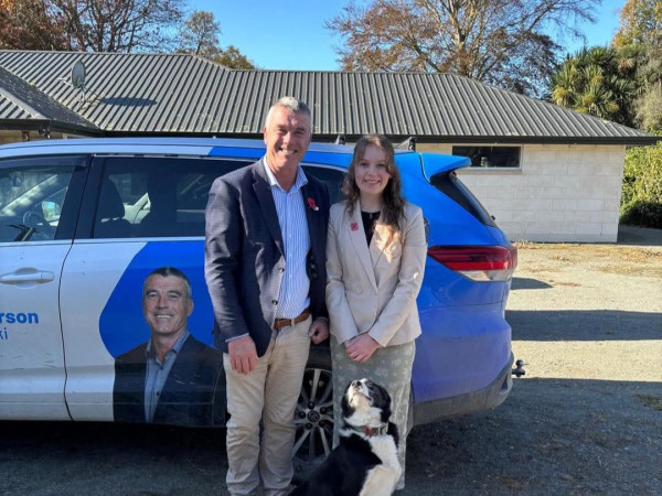 Youth MP Enya O'Donnell and MP Miles Anderson smile whilst standing in front of a blue car
