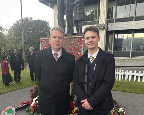 Chris Hipkins (left) and Ryan (right) stand in front of a board with poppies at an ANZAC commemoration