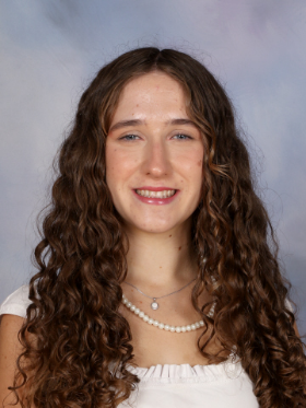 Emmogen Mckay smiles in front of a pale blue backdrop