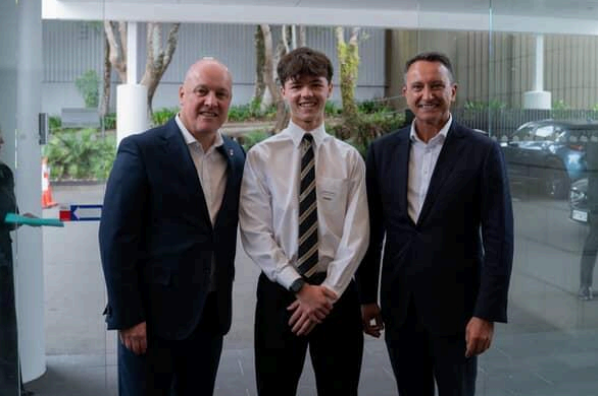 Jasper Rhodes stands with Prime Minister Rt Hon Christopher Luxon and David MacLeod in a building lobby