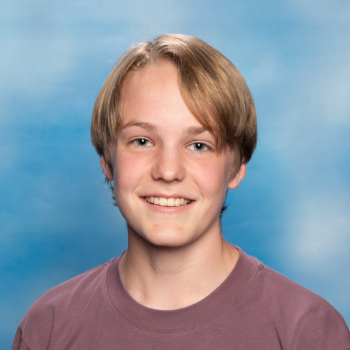 Youth MP Mackay Thomson smiling in front of a blue background
